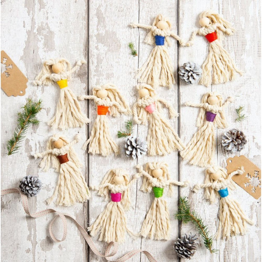Decorative angel figures with colourful accents on a wooden surface with pine cones and ribbons.