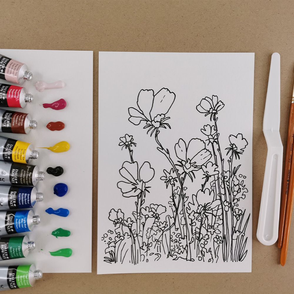 Art supplies including paint tubes and a floral drawing on a brown background