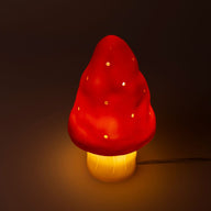 Mushroom-shaped lamp with red cap and yellow base on a dark background